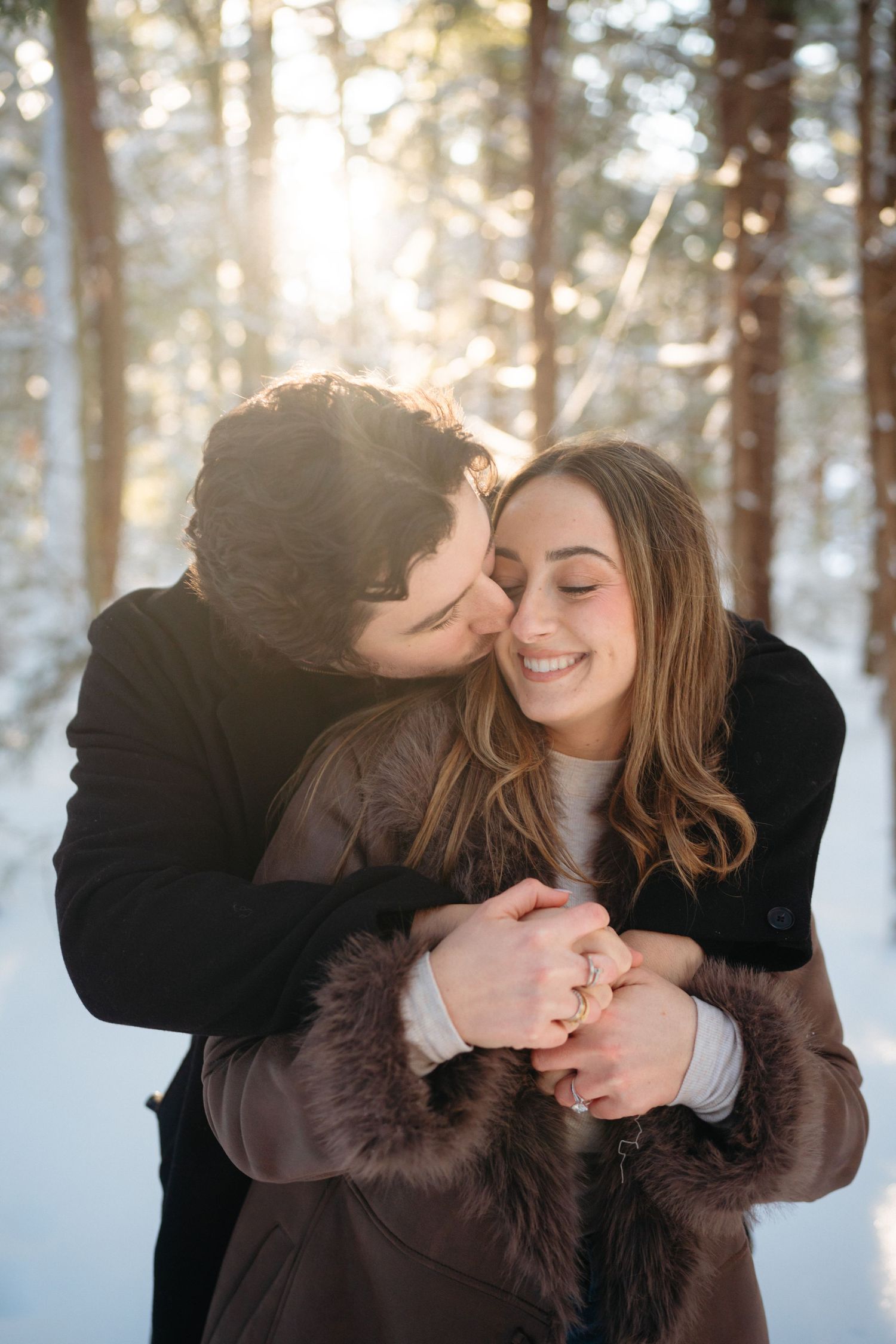 A romantic winter moment captured in a snowy forest with sunlight streaming through the trees.