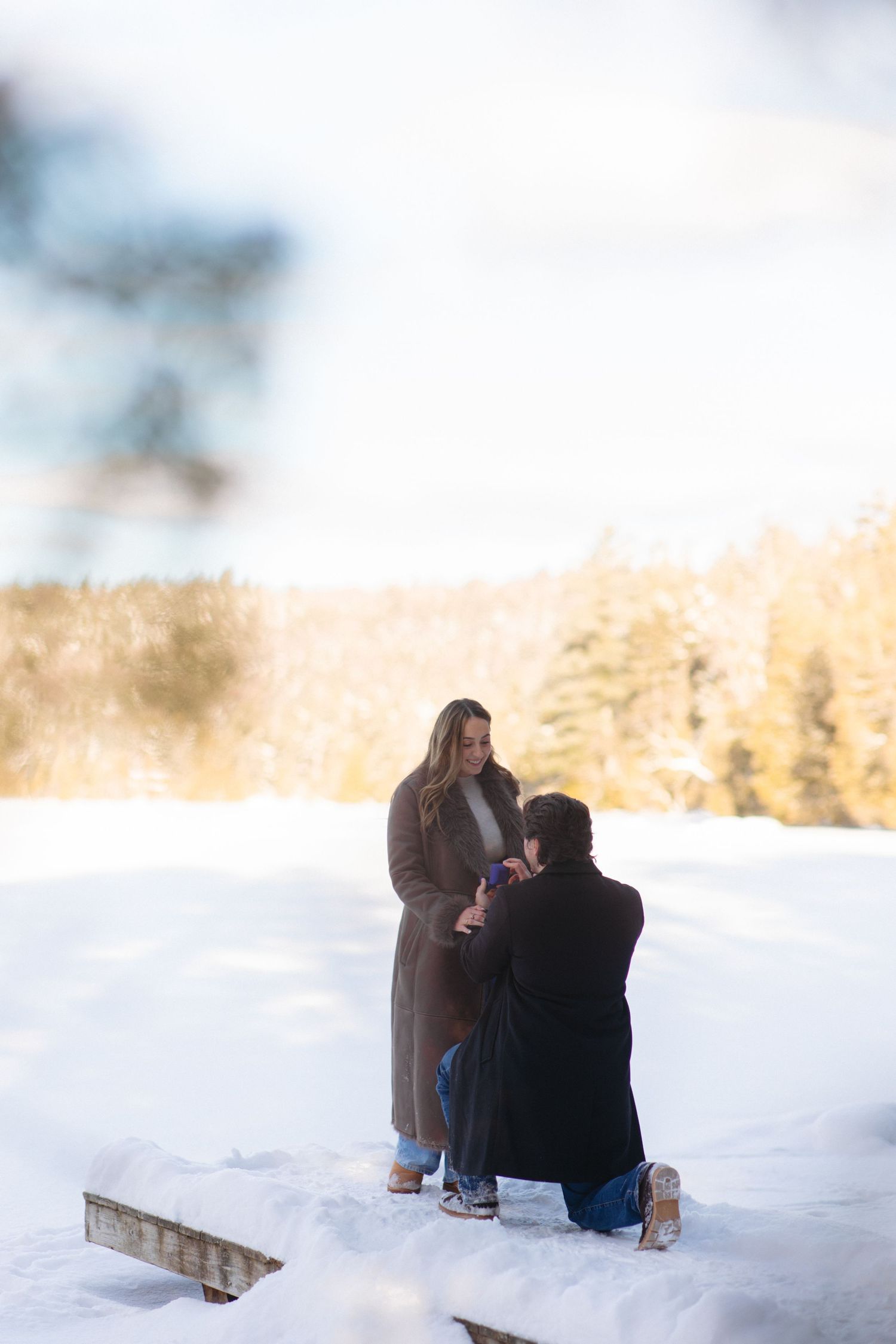 Two people sit together in a snowy winter landscape enjoying a peaceful moment outdoors.