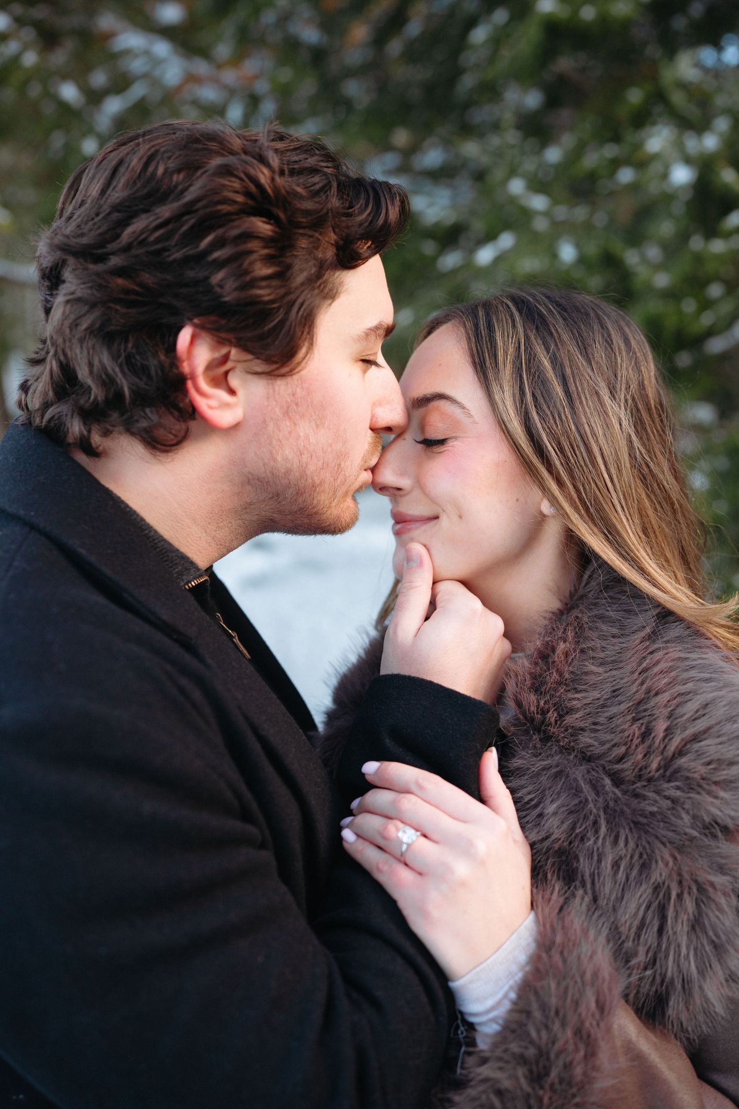 A romantic winter moment between a couple sharing tender kisses in the snow.
