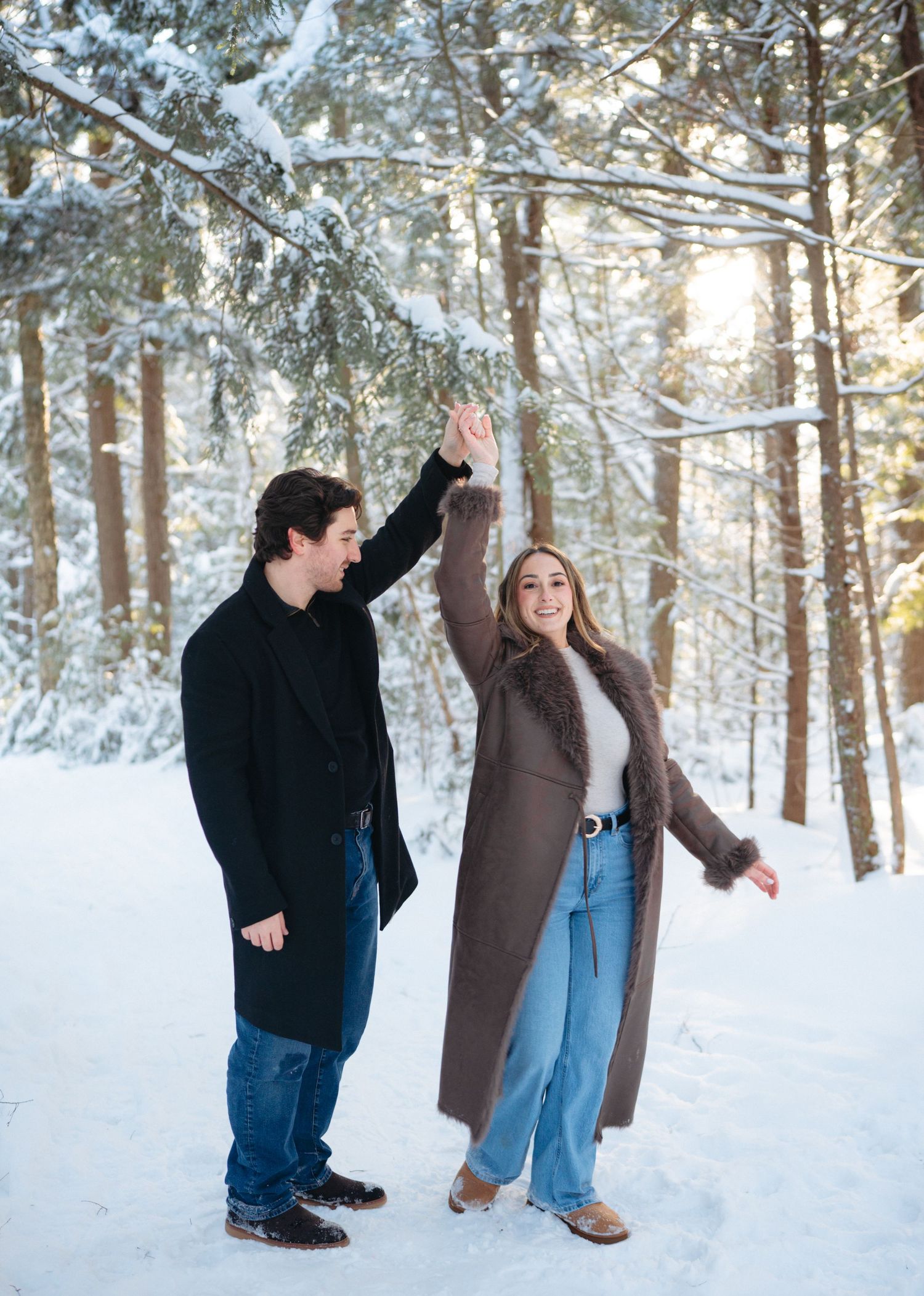 A playful couple enjoying themselves in a snow-covered forest setting.