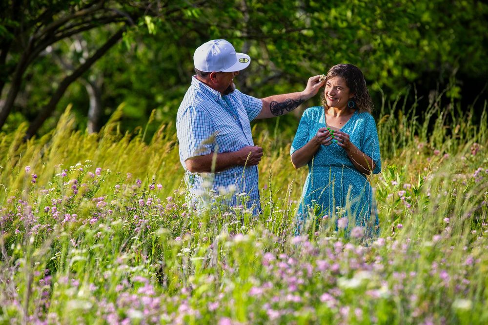 People interact in a sunny wildflower meadow wearing casual clothing.