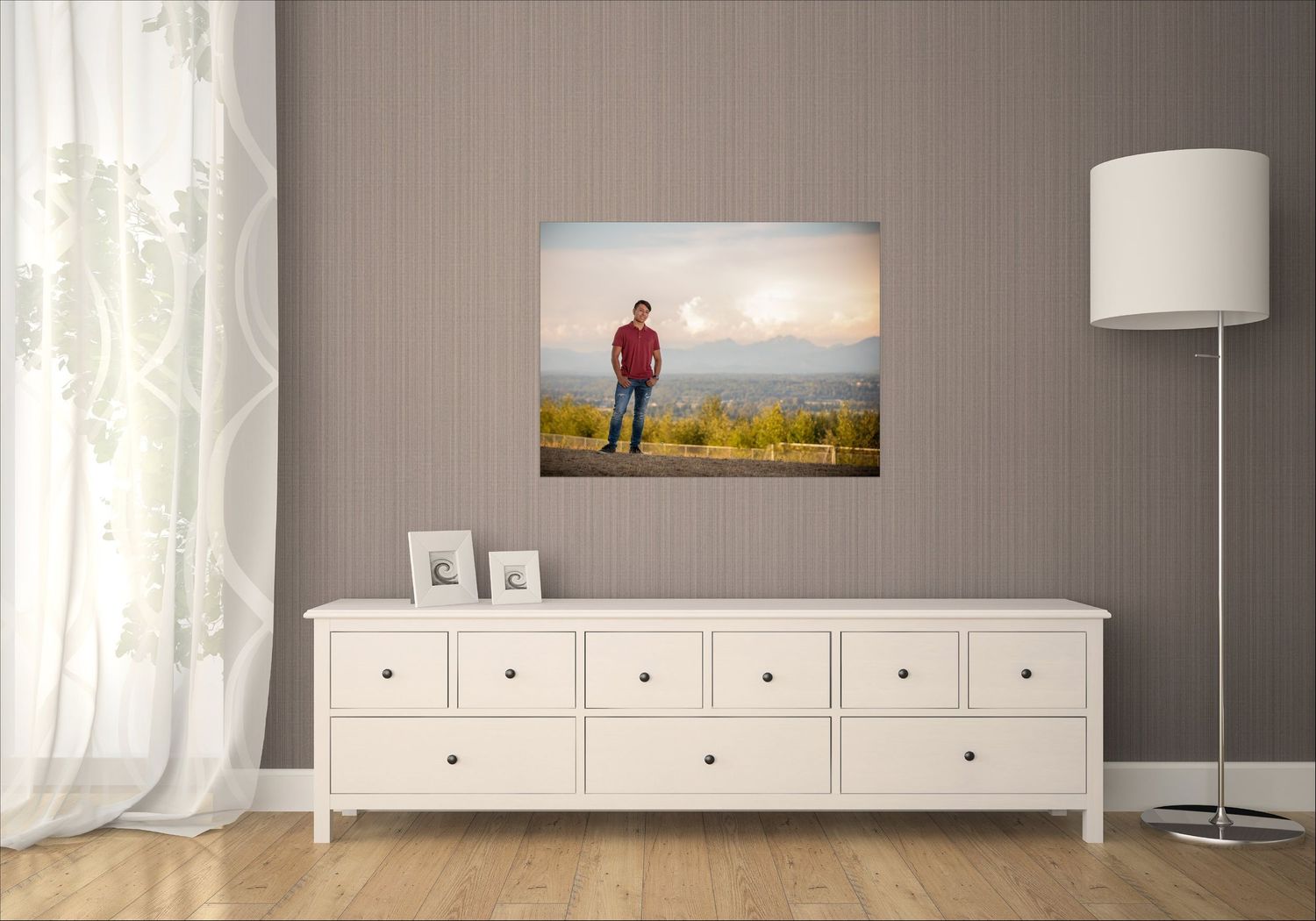 A modern minimalist living room with gray walls, white trim, and a series of framed artwork displayed in a row.