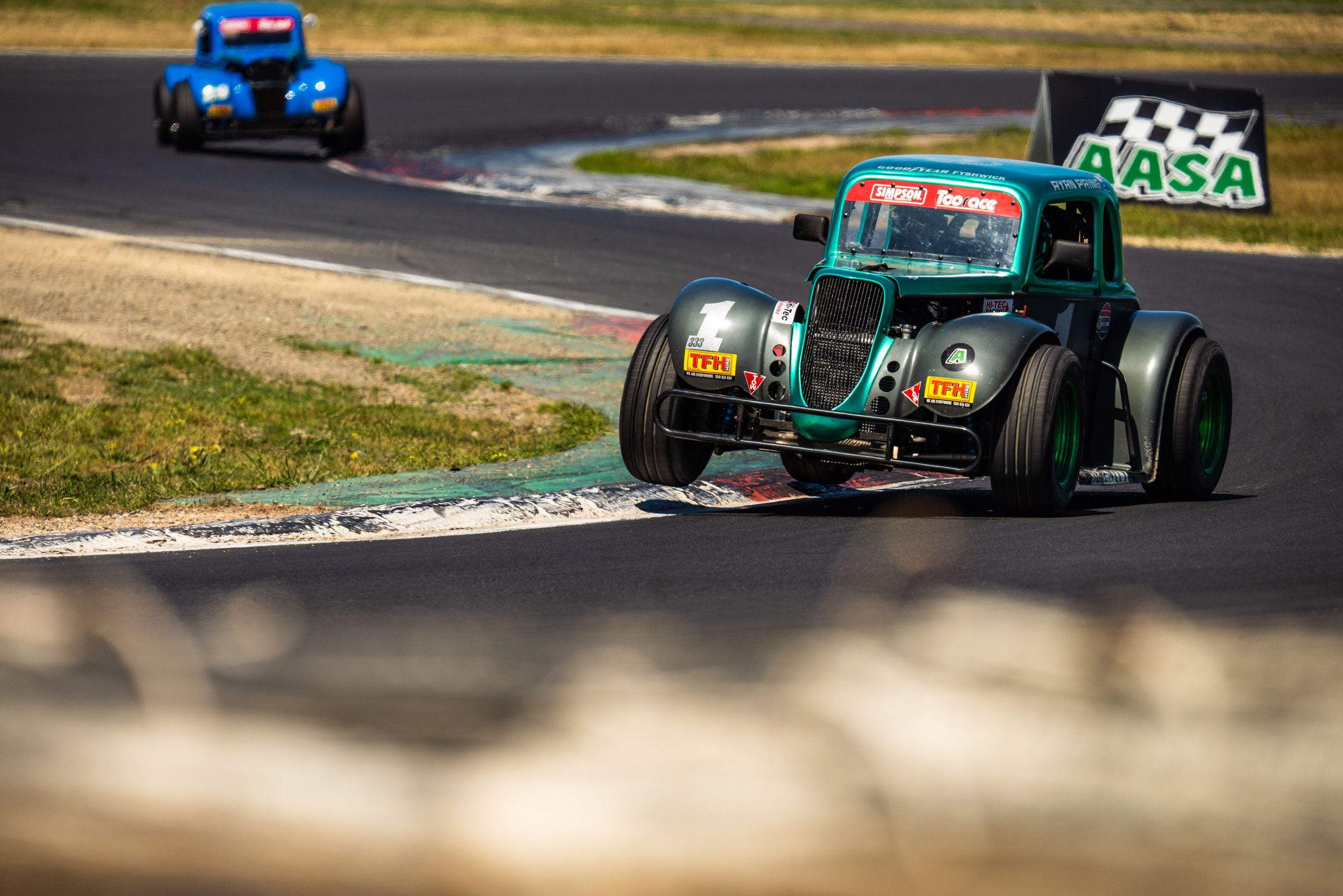 Formula racing car speeds around a racetrack corner during a competitive motorsport event.