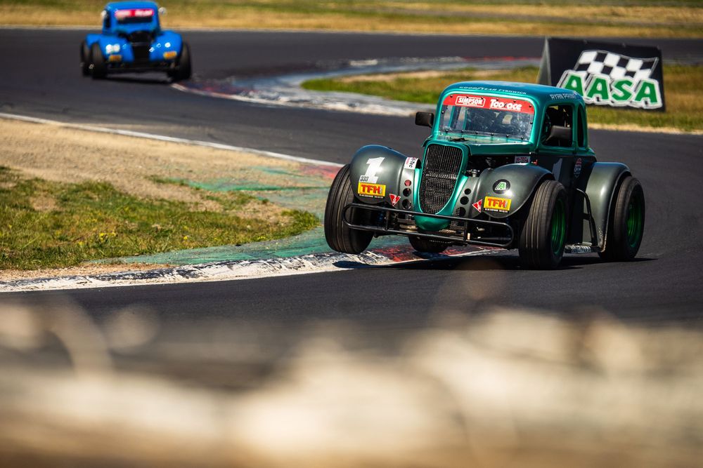 Formula racing car speeds around a racetrack corner during a competitive motorsport event.