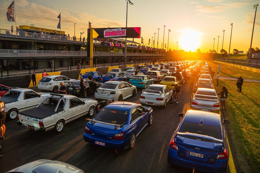 Cars lined up at sunset in a parking lot with golden sunlight streaming through the scene.