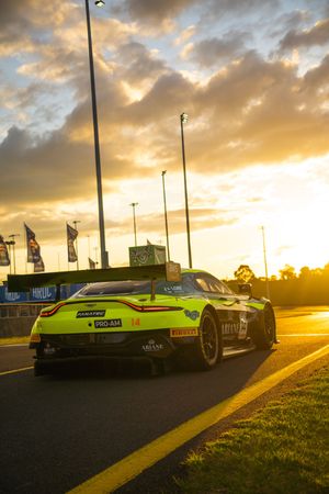 Four dramatic sunset photos of a sleek green sports car parked on a street with golden clouds in the background.