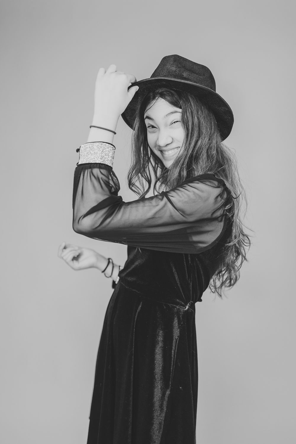 Dramatic black and white portraits with a black hat and flowing movements.