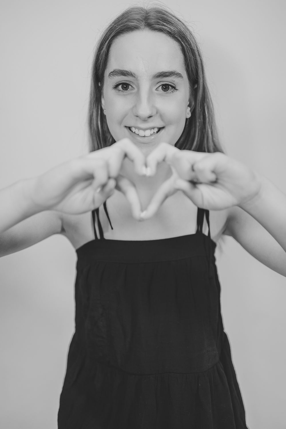 Black and white portrait series showing playful expressions and hand gestures against a light background.