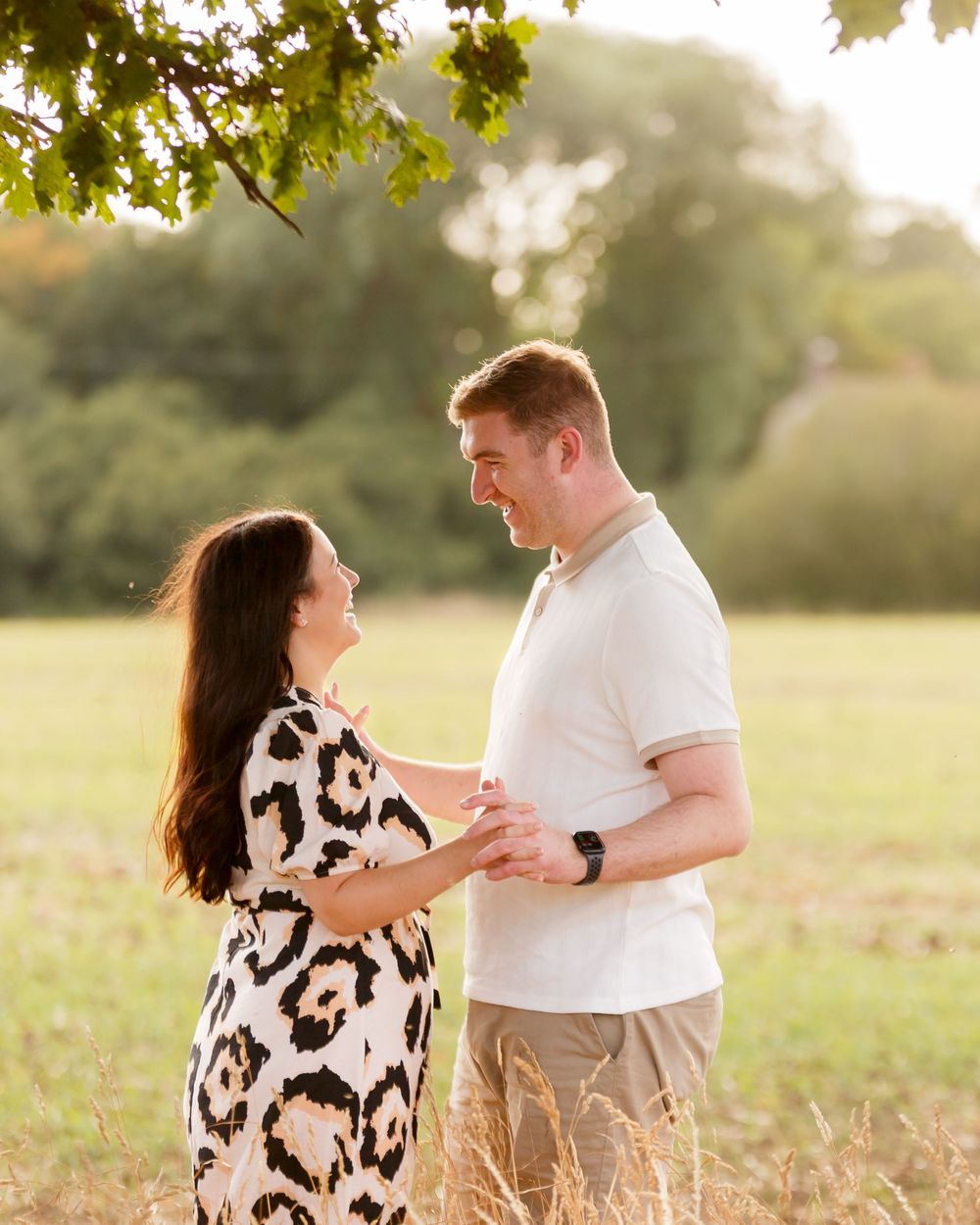 A couple embraces in a sunlit field during a romantic golden hour photo session in the countryside.
