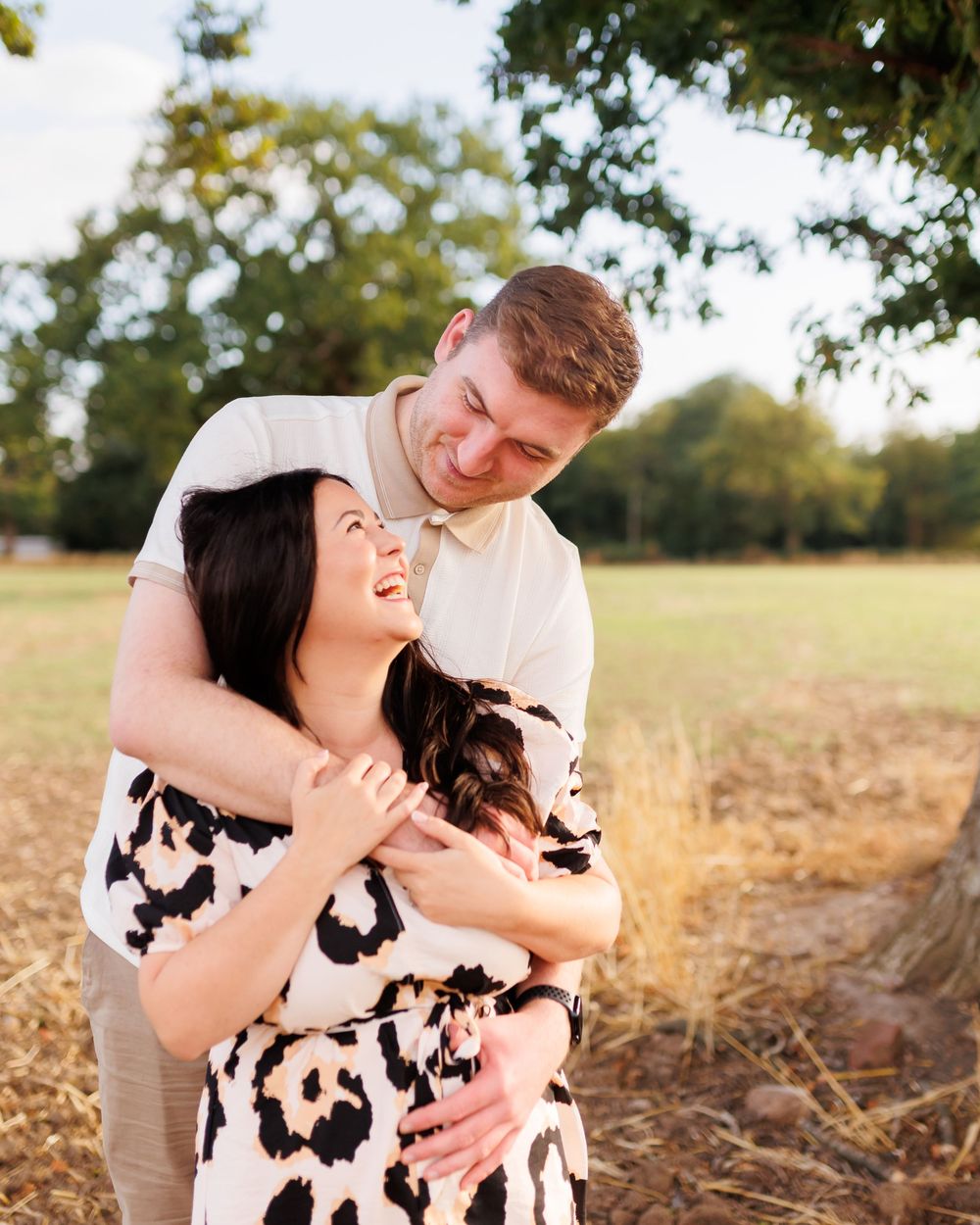 Intimate moment captured between couple in black and white dress against natural outdoor setting.