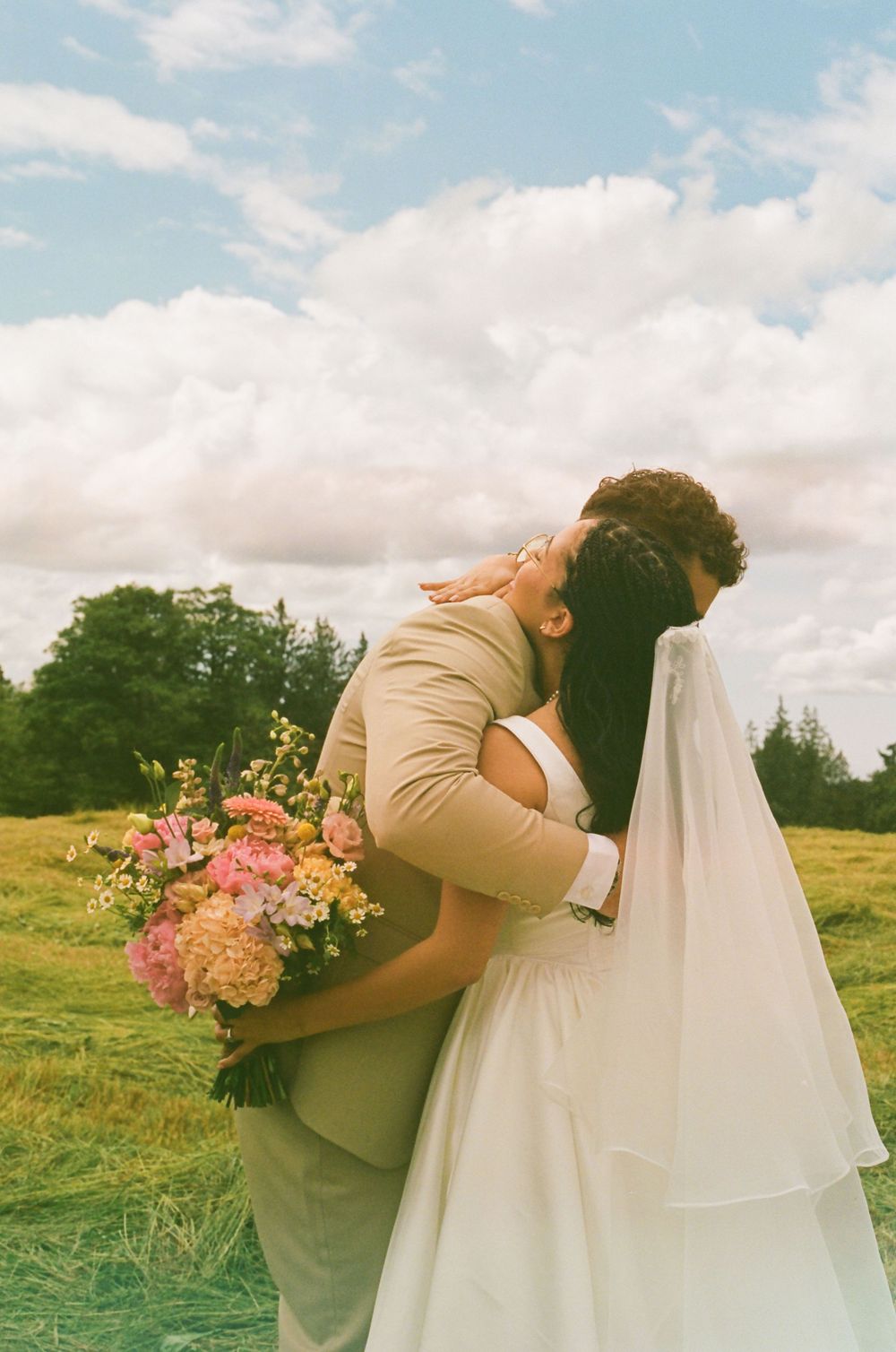 Romantic wedding photo sequence showing couple embracing in a green meadow with pink flowers.