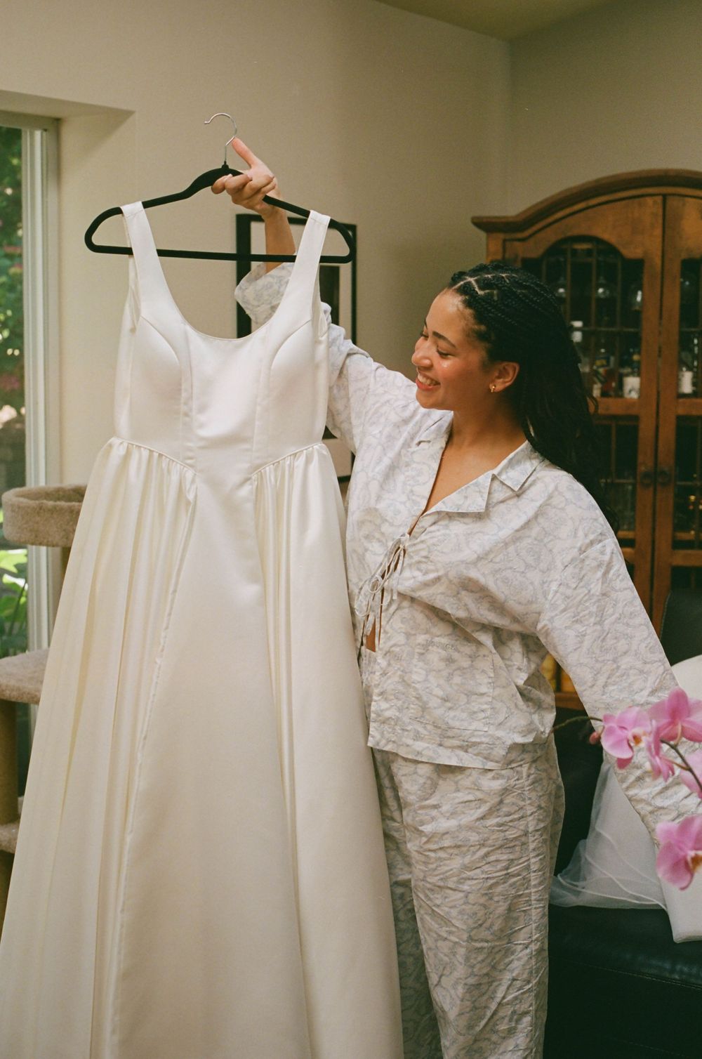 White wedding dress displayed on a hanger while being prepared indoors.
