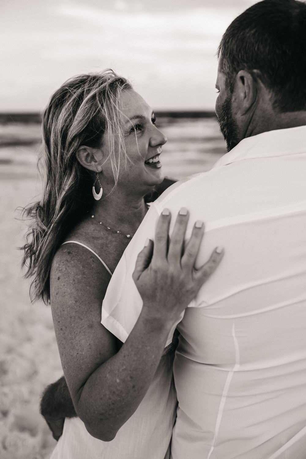A series of black and white beach photos showing a couple sharing intimate and joyful moments together.