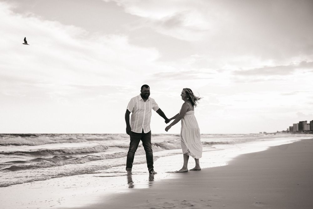 Romantic silhouettes of couple walking together along a tranquil beach at sunset.