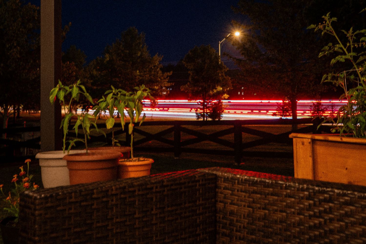 Long exposure nighttime photo showing red light trails curving along a neighborhood road