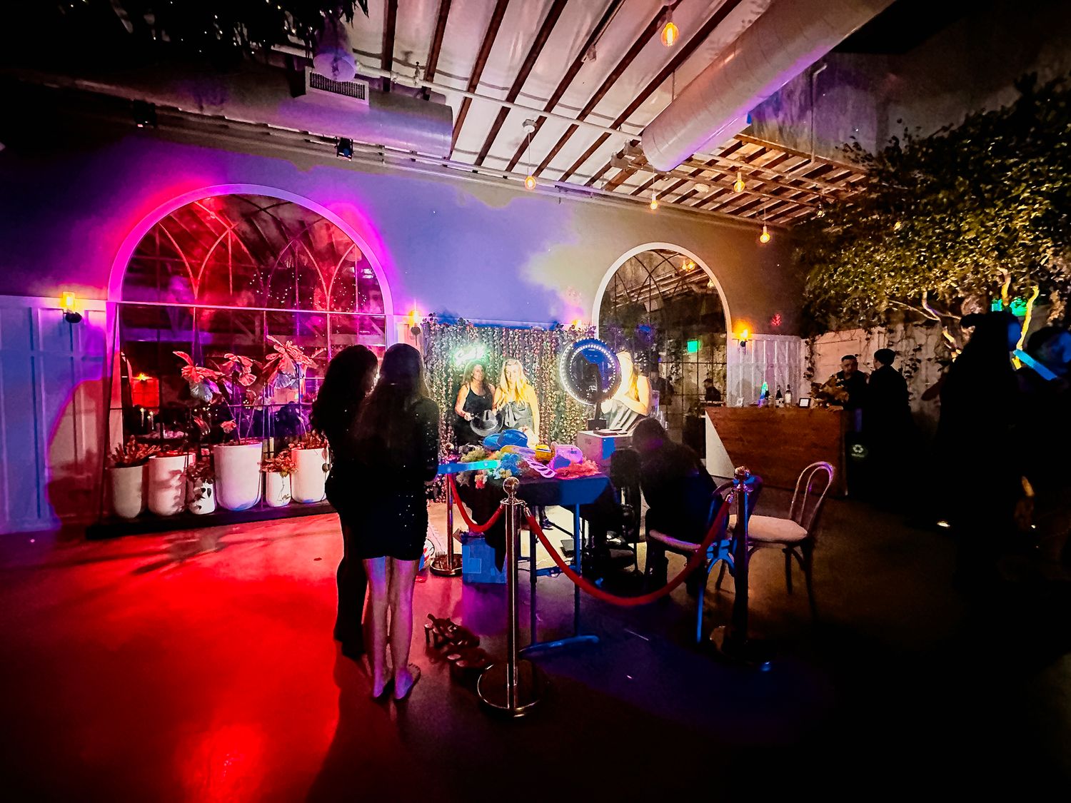 Event venue illuminated with colorful mood lighting and decorative elements, highlight our Signature Photo Booth.