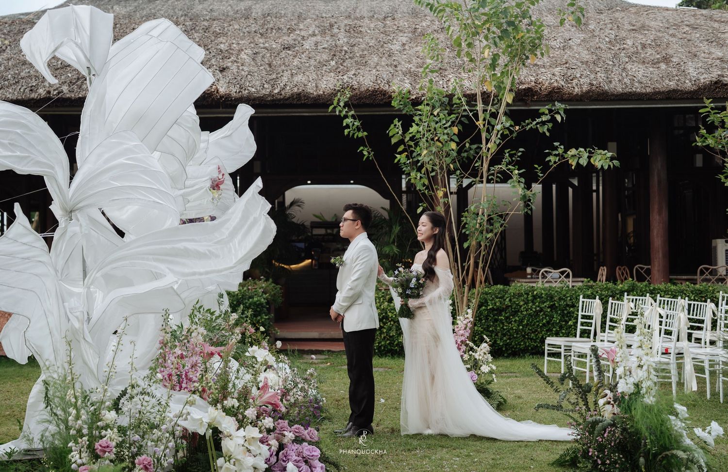 Couple sharing first look moment at outdoor garden wedding with white floral decorations.