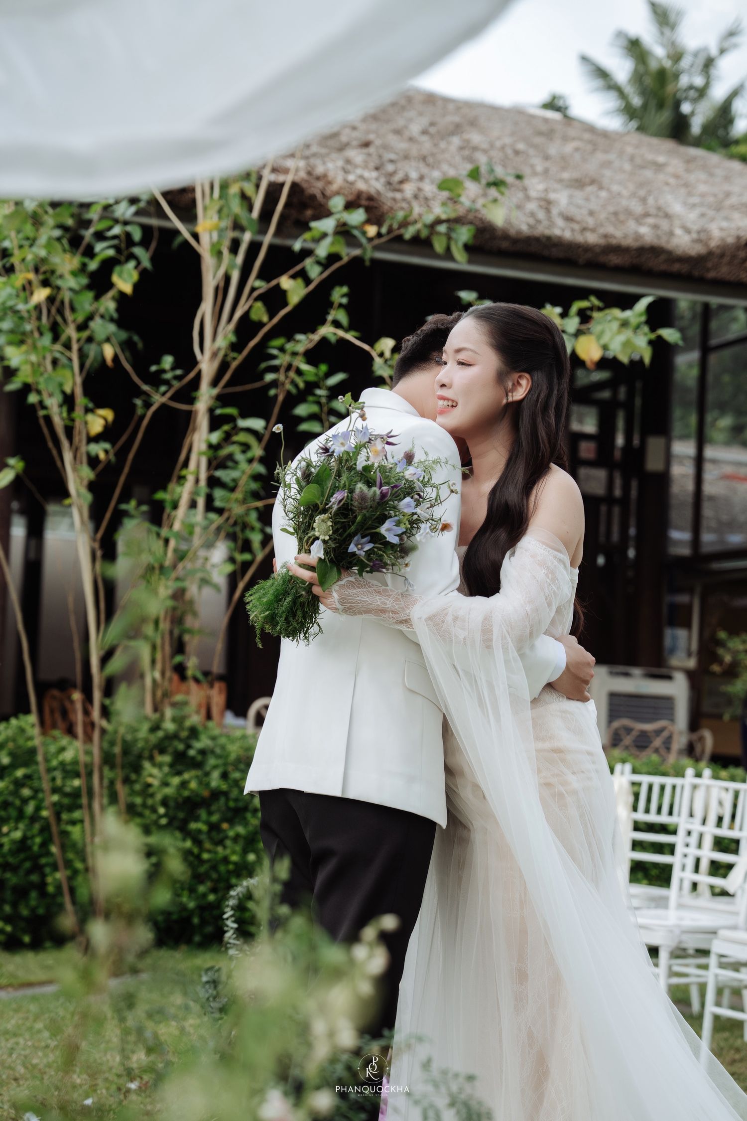 Bride and groom sharing emotional embrace at outdoor garden wedding ceremony.