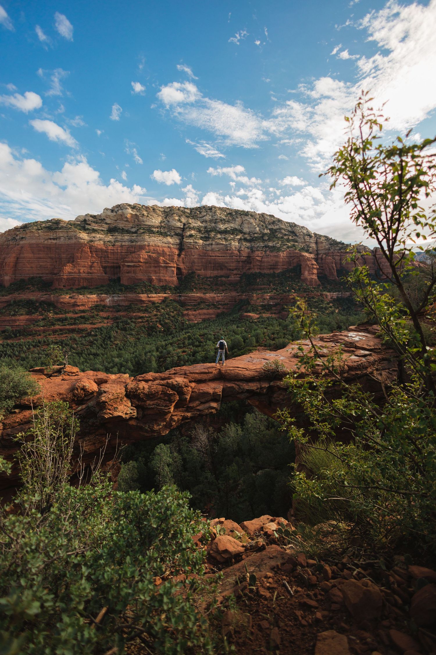 Solo traveler walking barefoot on desert road with camera in hand, Utah red rock cliffs. Adventure lifestyle photography by MannyPortraits.