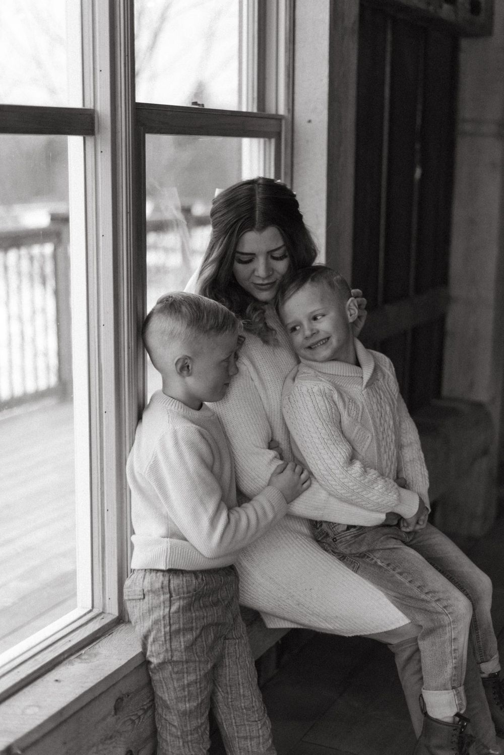 A tender family moment shared by a window with soft natural lighting streaming in.