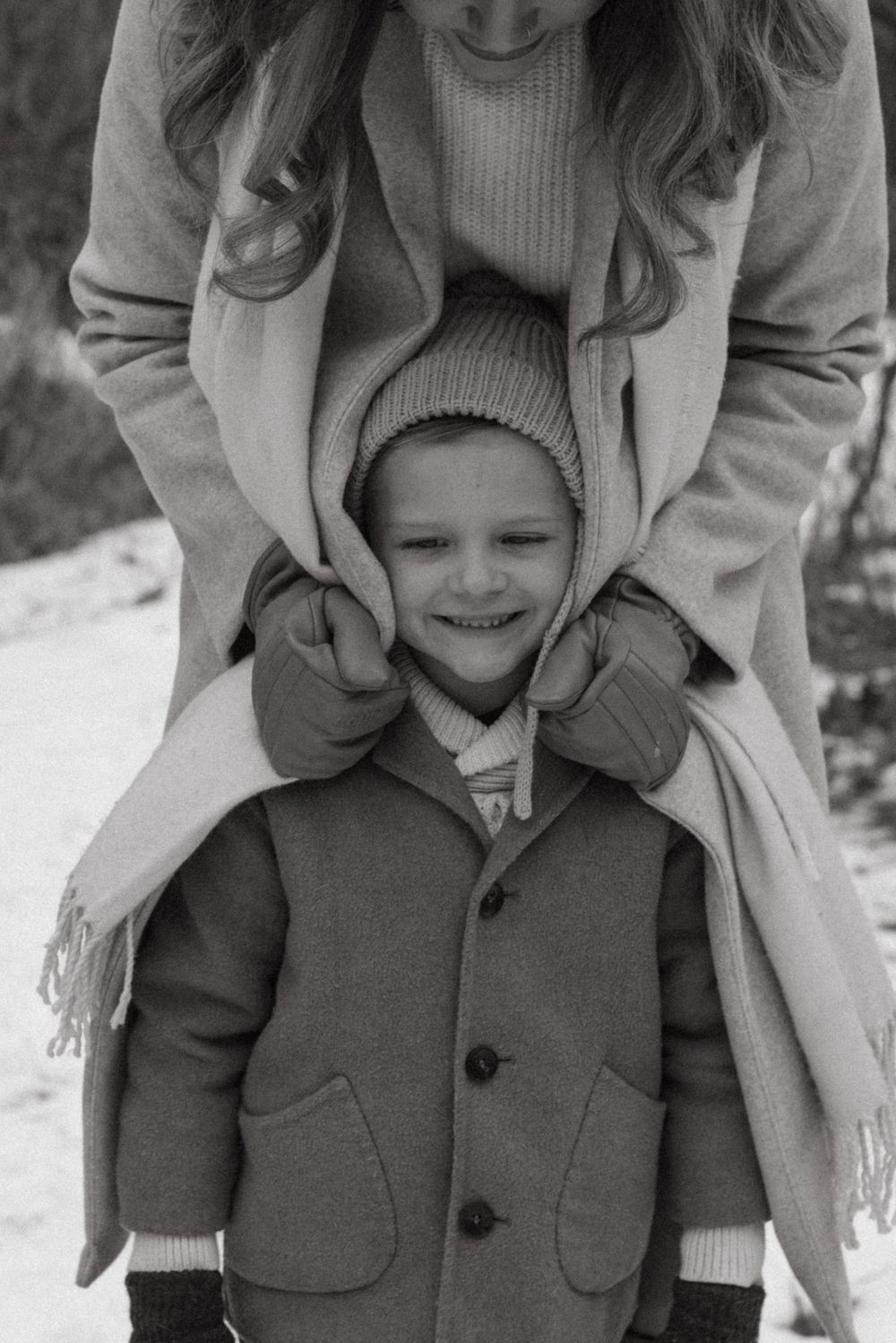 Series of black and white photos showing a child in a winter coat and a person behind them smiling outdoors.