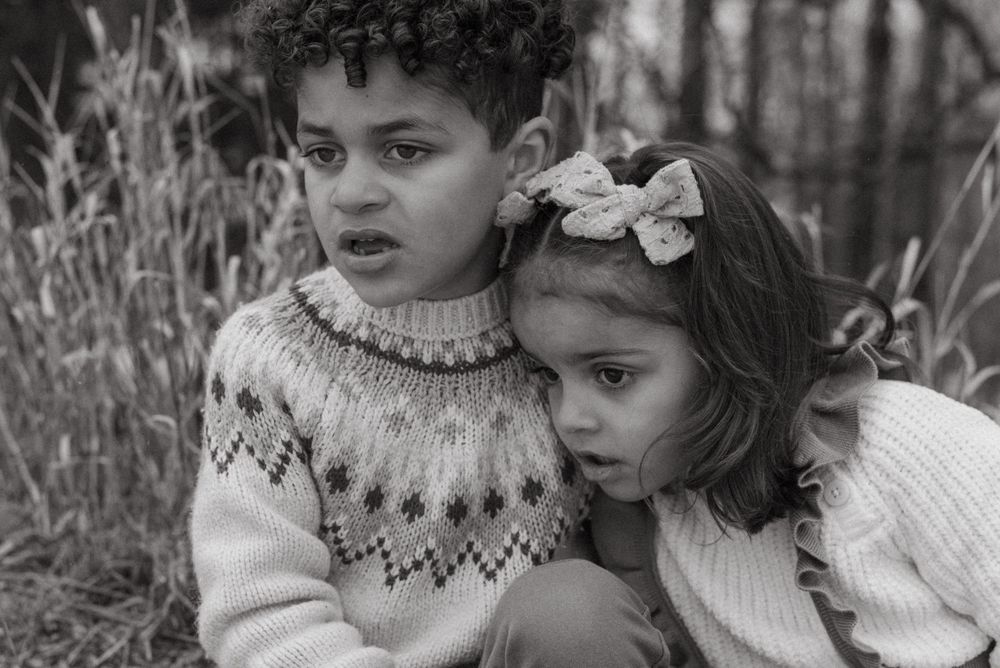 Vintage black and white portrait of two young children in sweaters showing tender closeness and innocence.