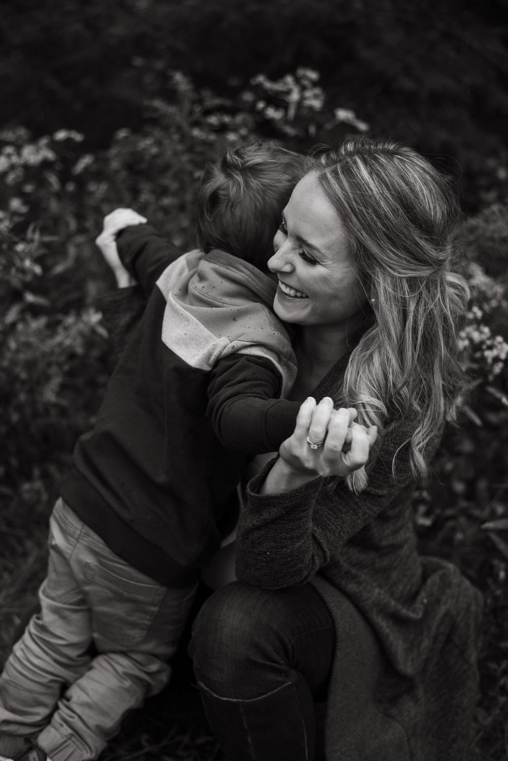 Black and white photo series showing a heartfelt embracing moment between two people sharing genuine laughter and connection.