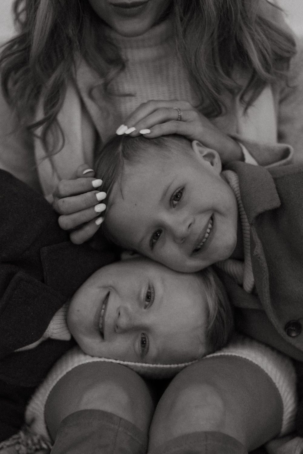A black and white intimate family portrait showing tender moments of affection and joyful smiles.