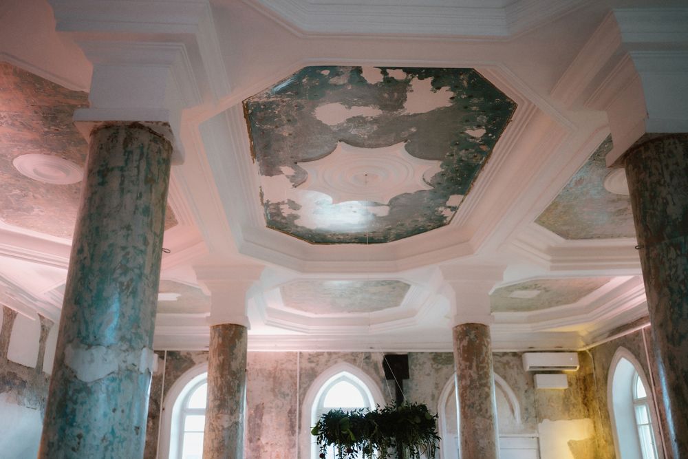 Ornate ceiling with decorative moldings and columns in a historic building interior.