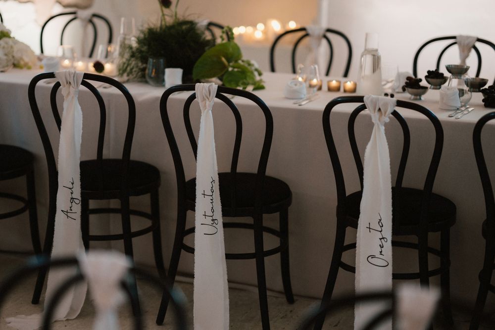 Reception chairs with white fabric sashes tied elegantly on dark bentwood frames.
