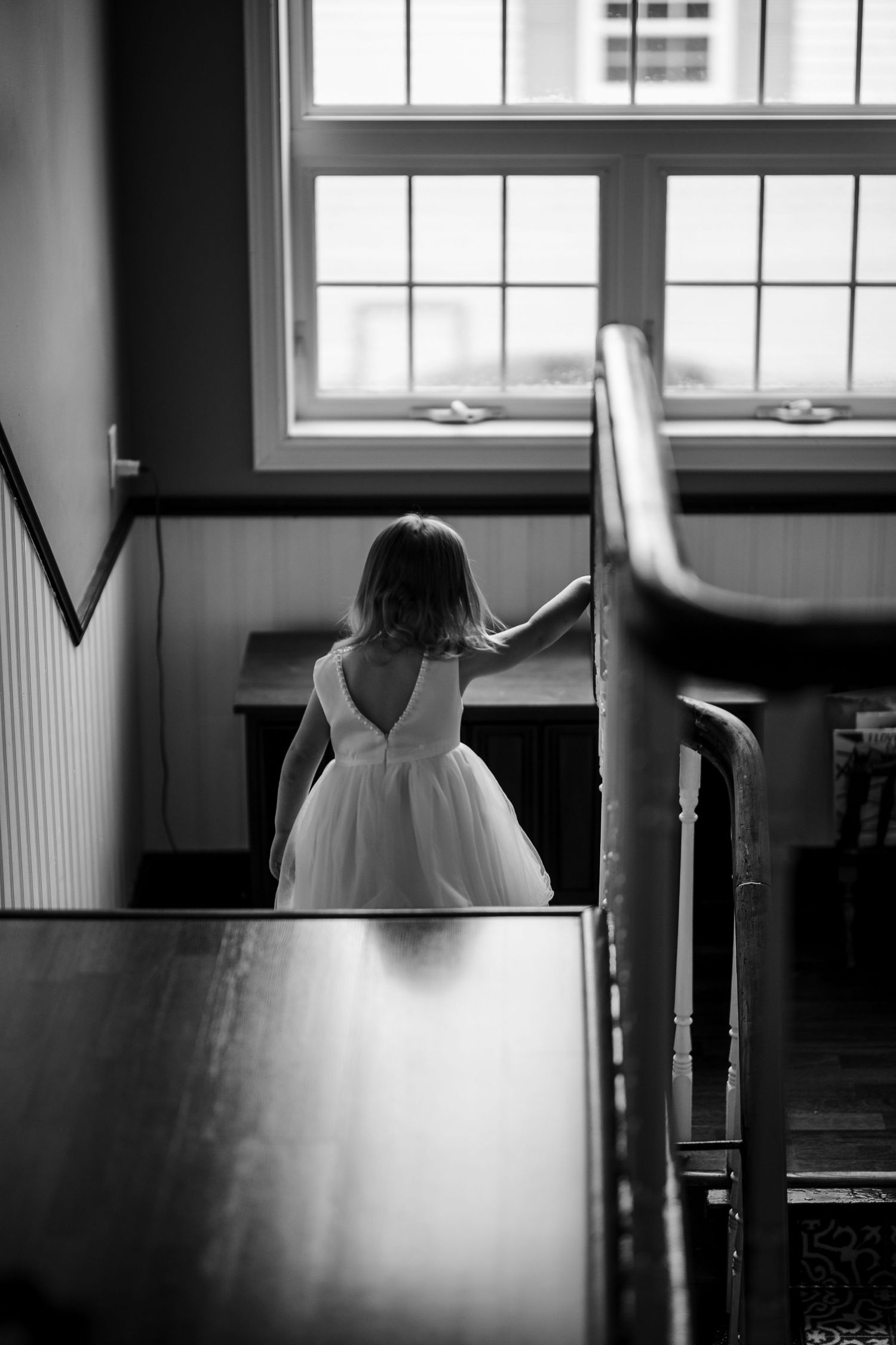 A series of four moody black and white photographs showing silhouetted figures in a window-lit interior space.
