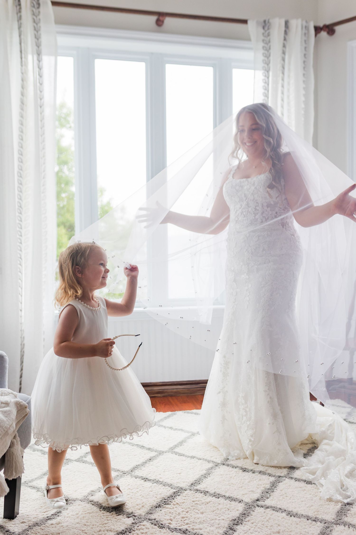 Little girl in white dress dances and twirls through sunlit room with flowing white curtains.
