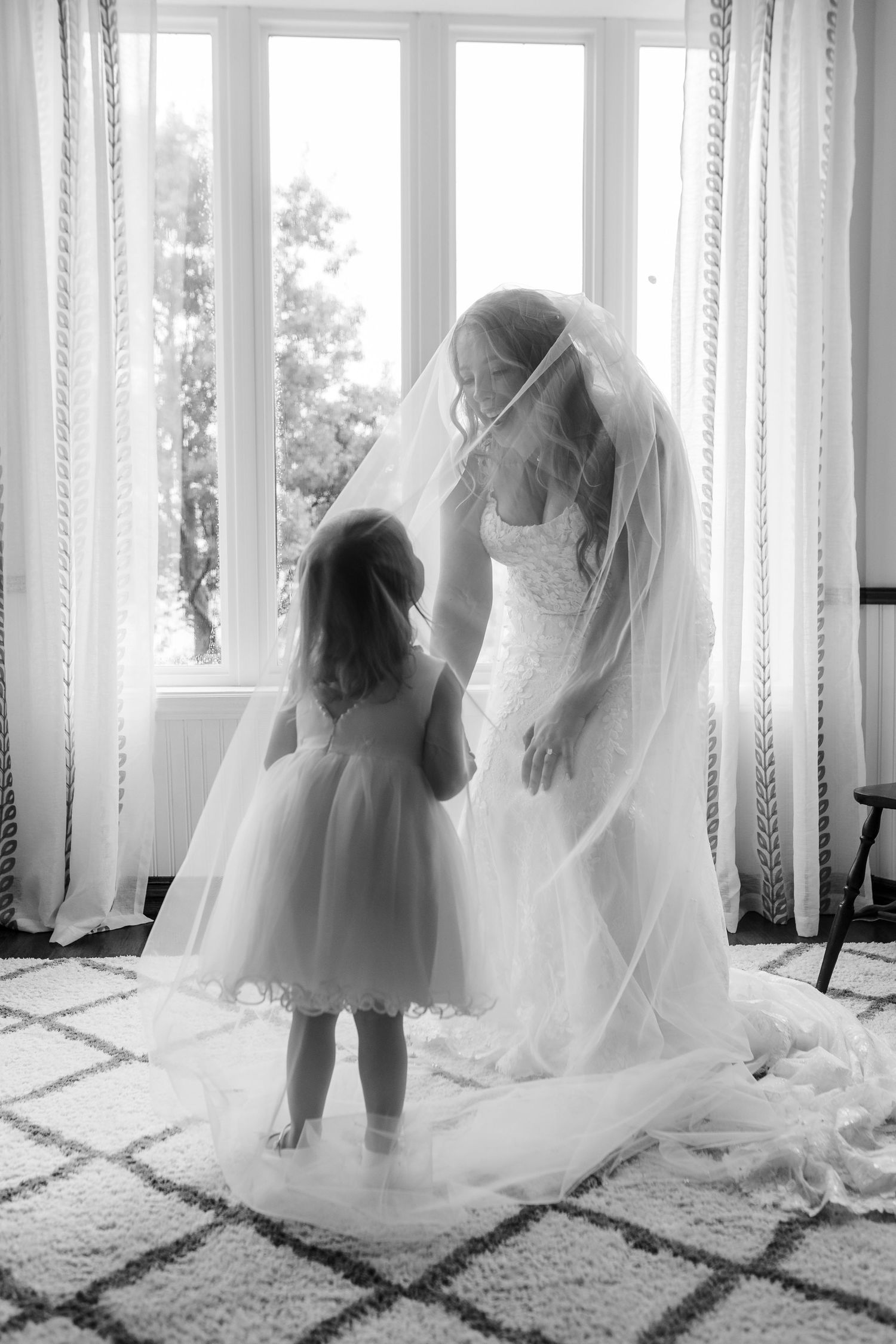 Series of black and white photos showing young child playing with flowing white fabric and curtains near windows.