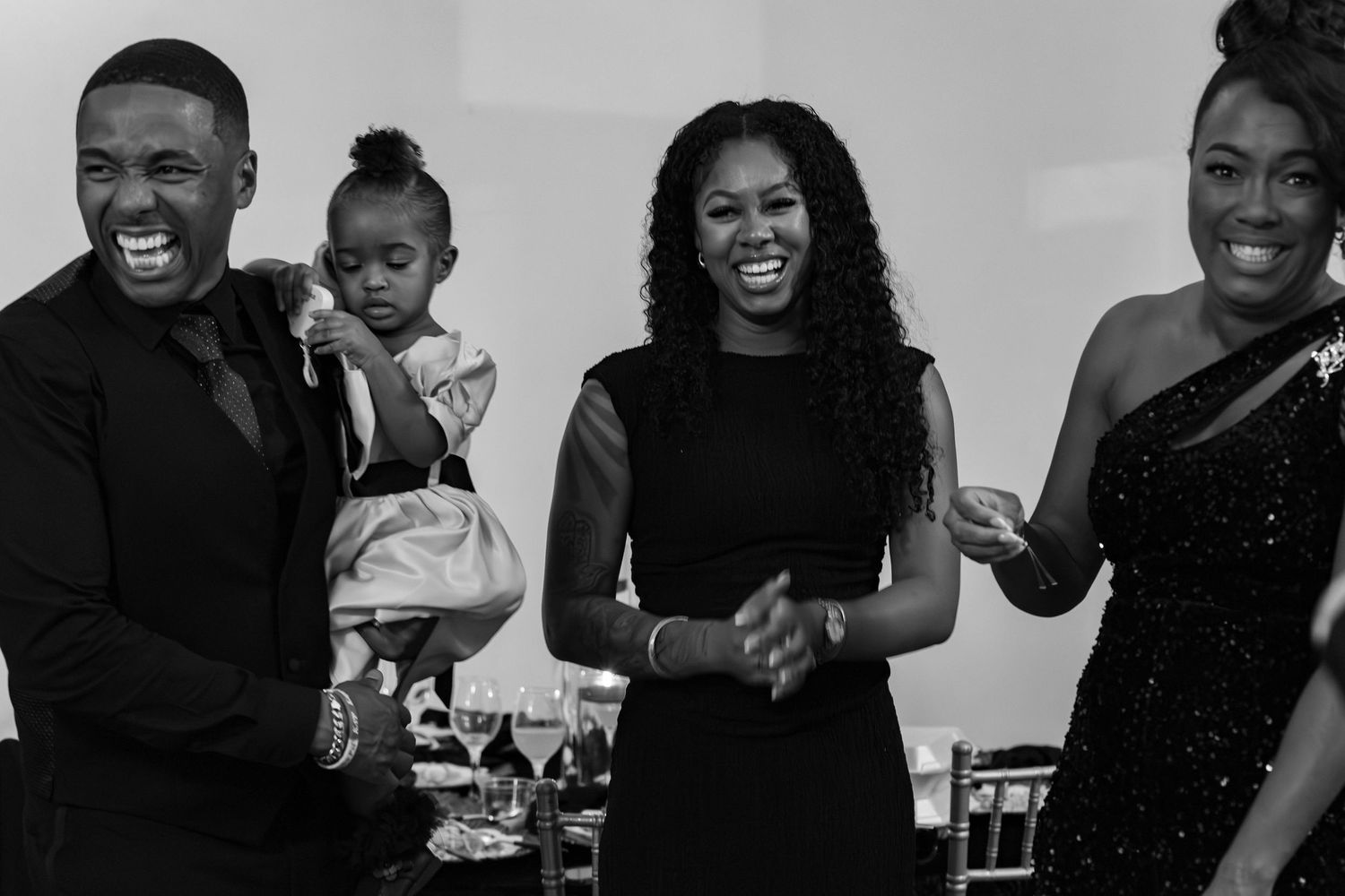 Black and white photo of joyful guests laughing and dancing at an elegant formal celebration event.