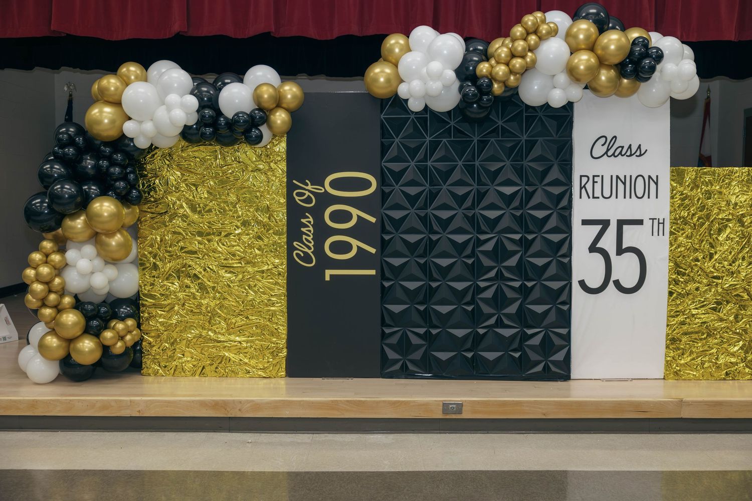 Class of 1990 35th reunion decorative backdrop with gold and black balloons on stage.