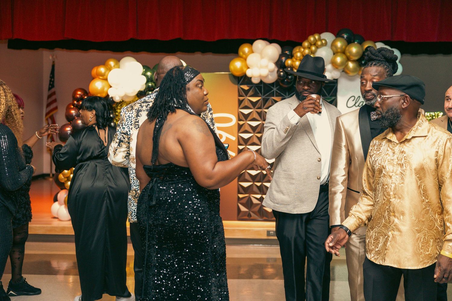 Guests mingle and converse at an elegant black and gold themed celebration event.