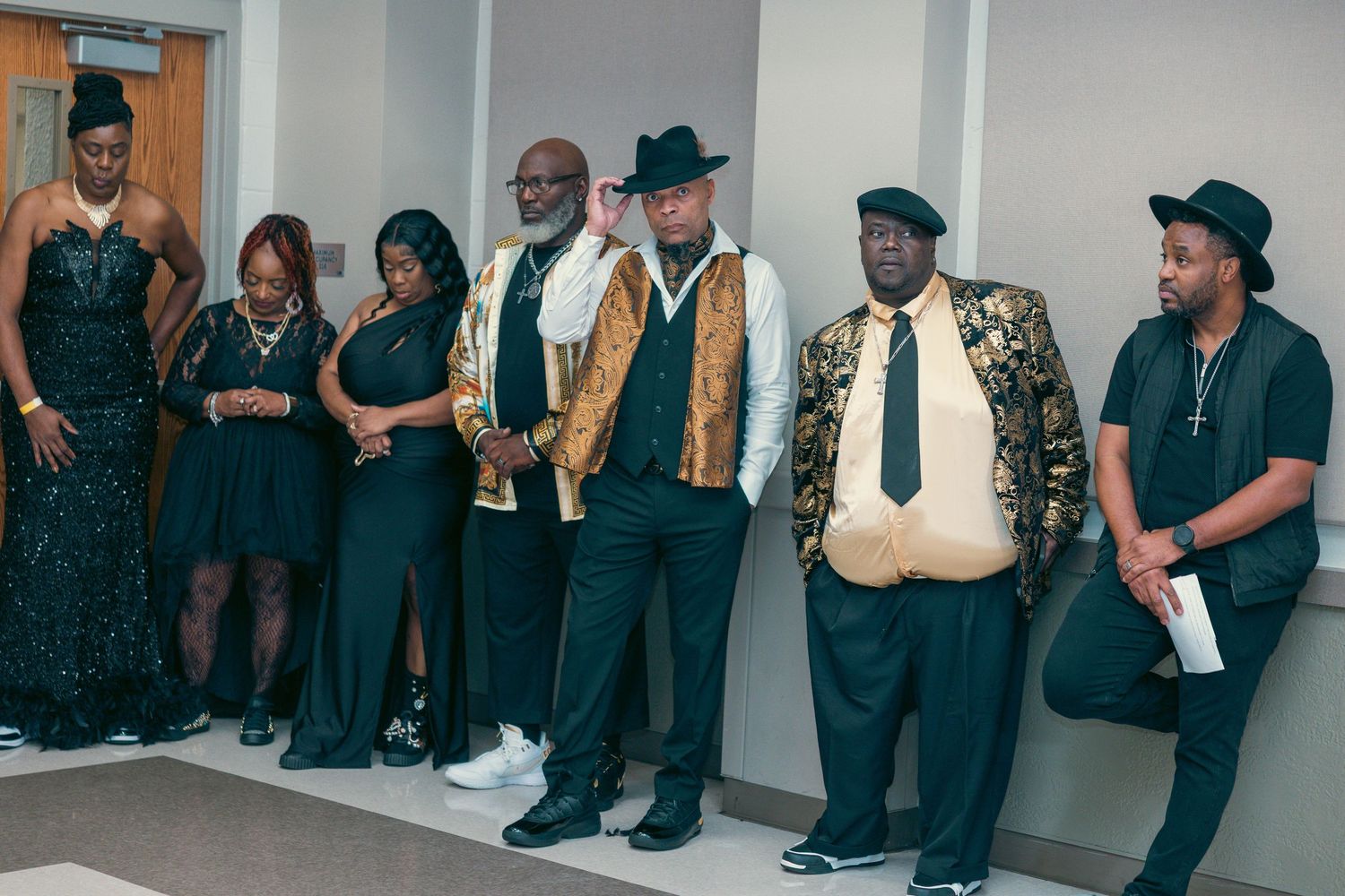 Group of elegantly dressed people in black and gold outfits posing at a class reunion event.