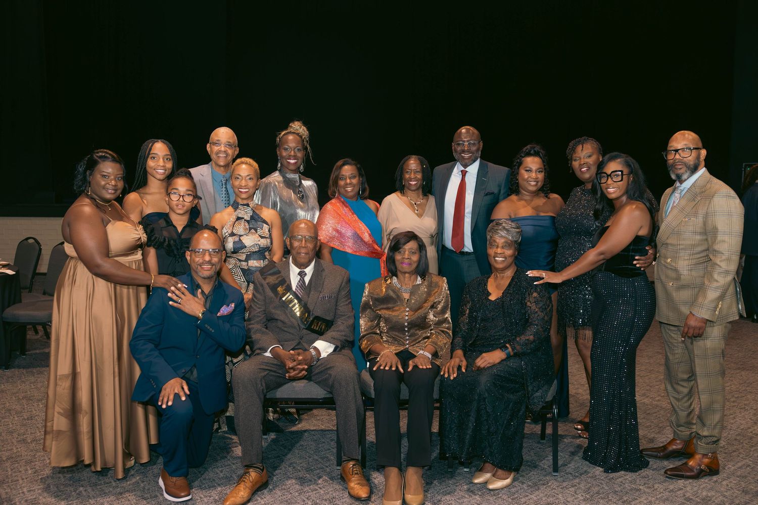 Large group of formally dressed guests pose together for photo at celebration event.