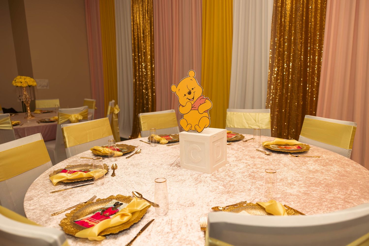 Elegant Winnie the Pooh themed table setting with gold and pink decor.