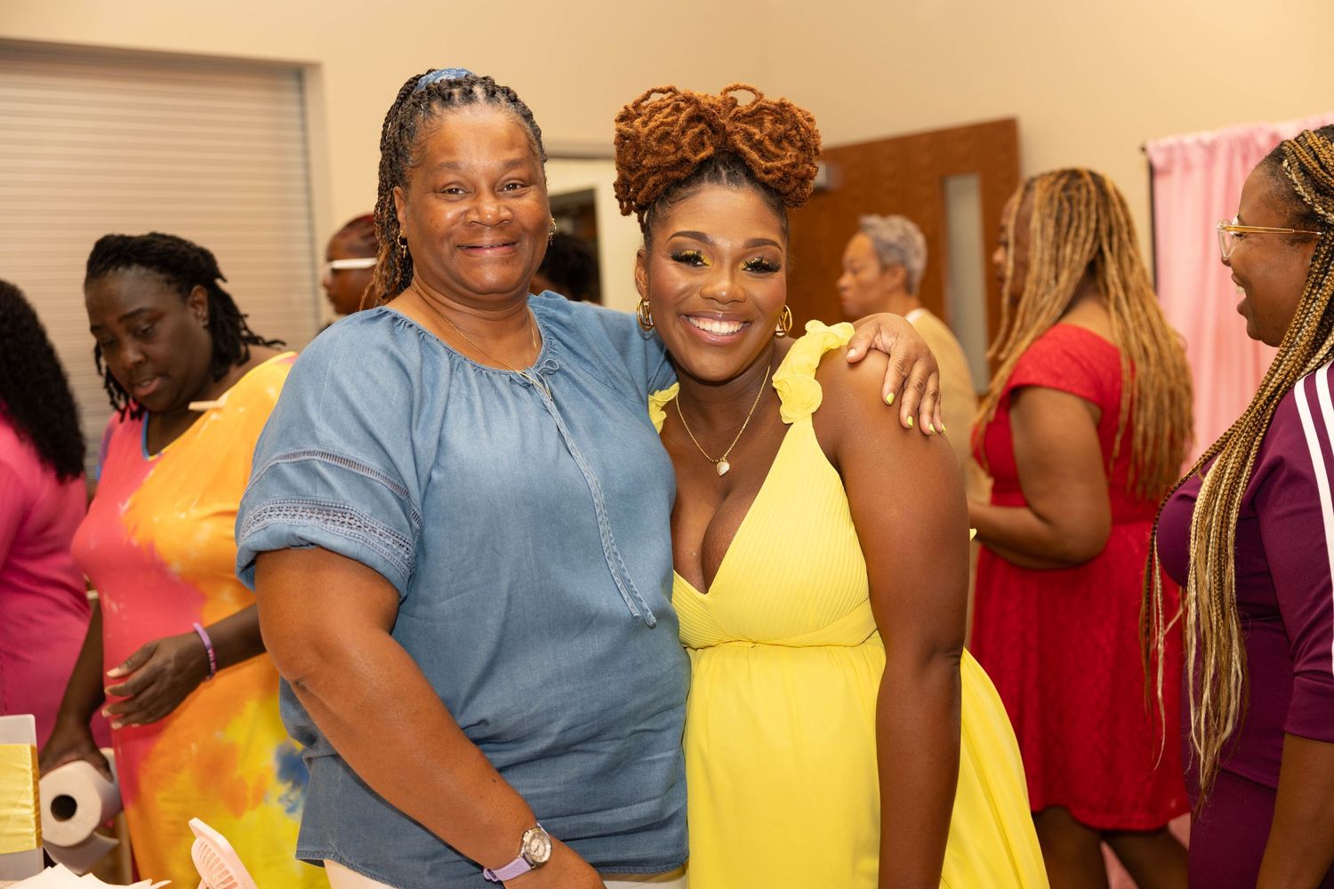 Two women smiling together at a colorful baby shower celebration.