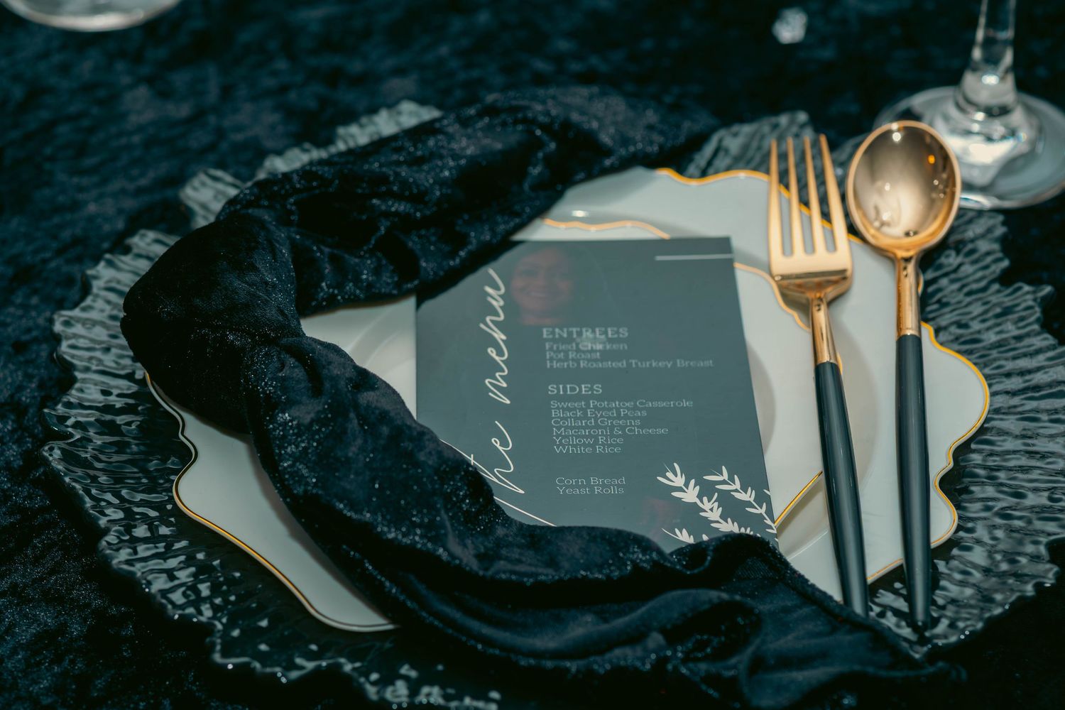 Luxury black and gold place setting featuring velvet napkin, gold cutlery, and decorative menu card.
