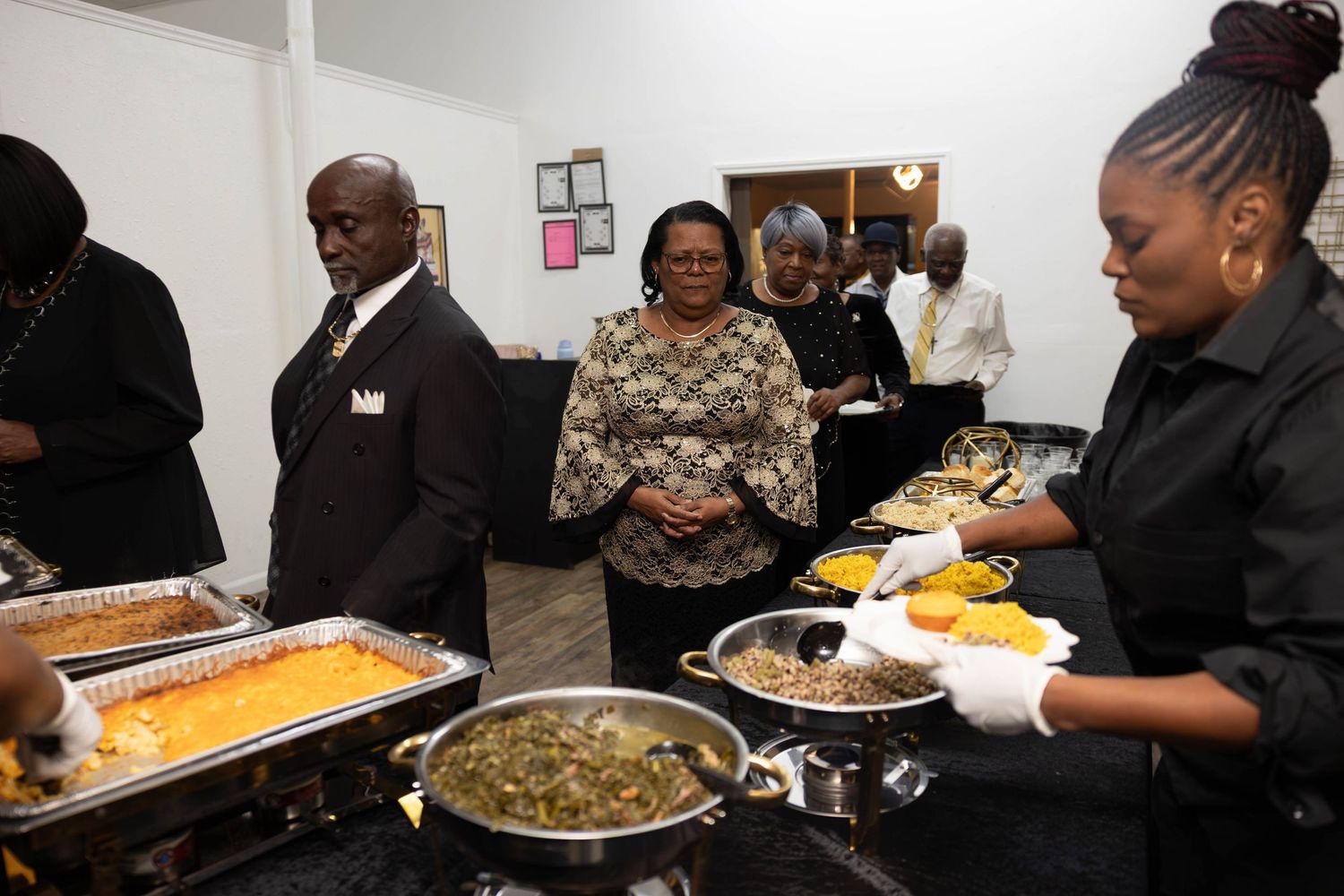 Guests being served at a catered buffet with multiple chafing dishes at an elegant formal event.