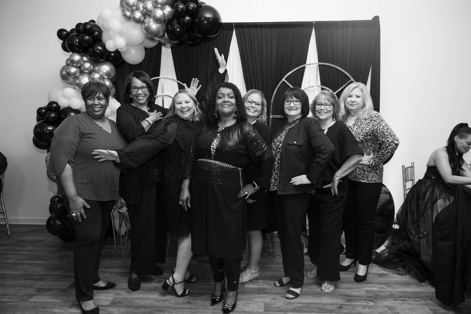 Group of women smiling together at a black and gold themed event in black and white photo.