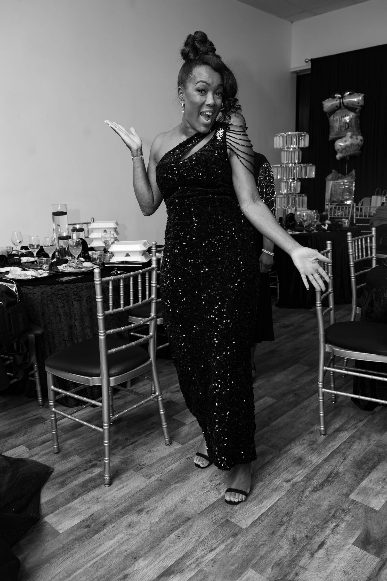 Woman in sparkly black gown posing gracefully at an elegant event in black and white photo.