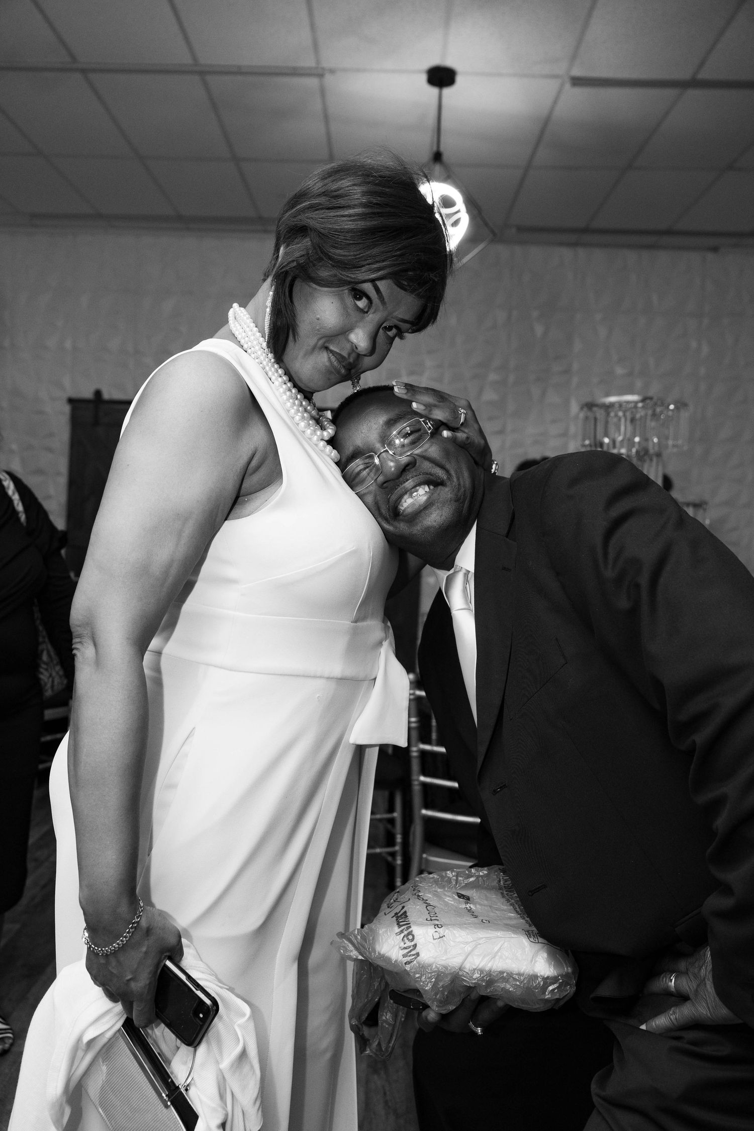 Couple sharing a joyful moment at a formal event, woman in white dress, man in suit.