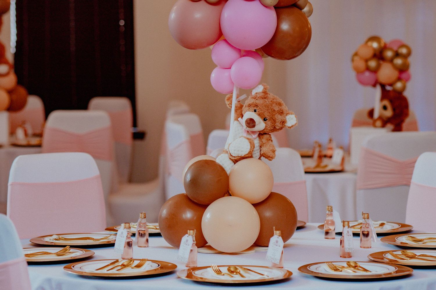 Pink and brown teddy bear baby shower table centerpiece with balloon decorations.
