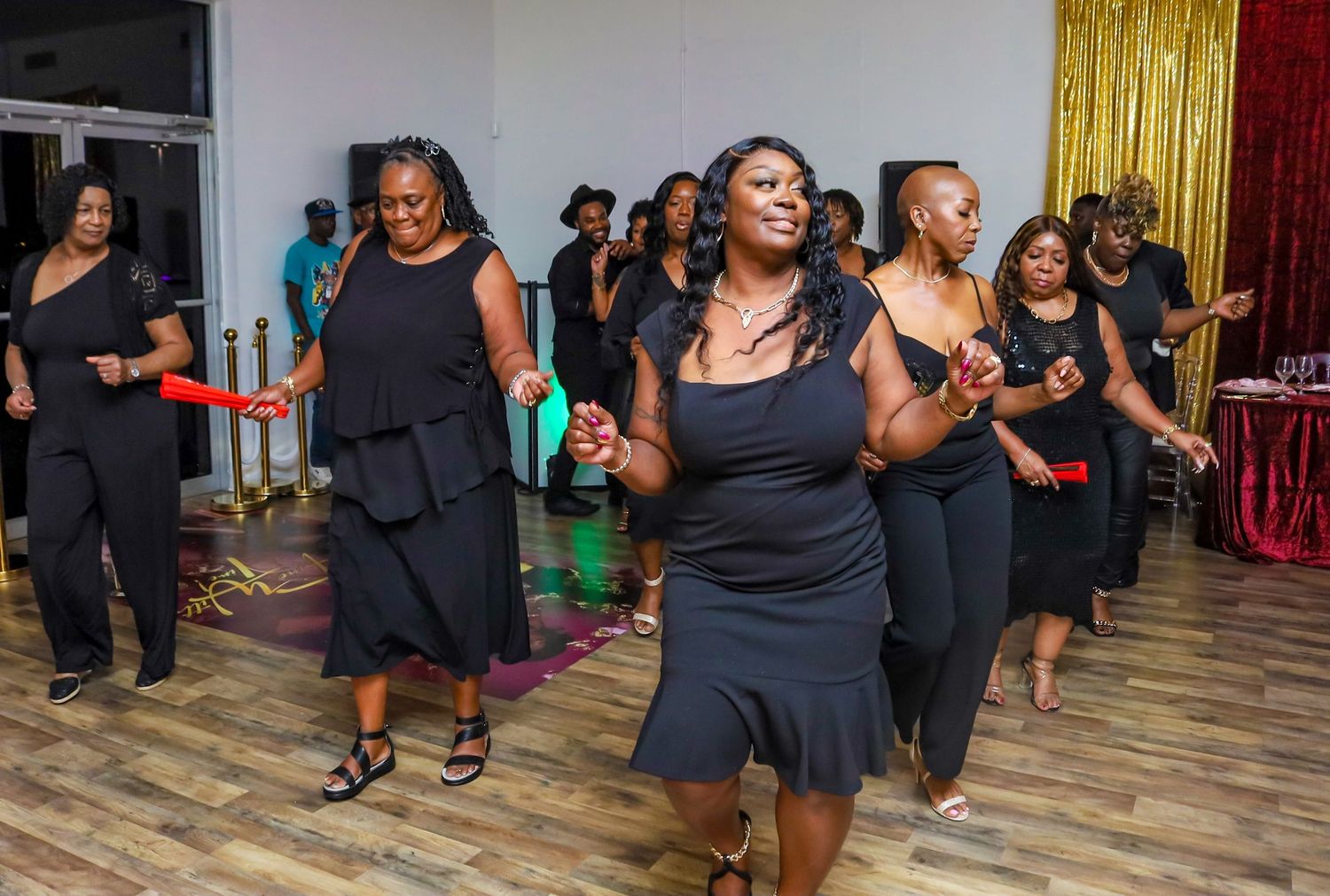 Women in matching black outfits dancing together at a celebratory party event.