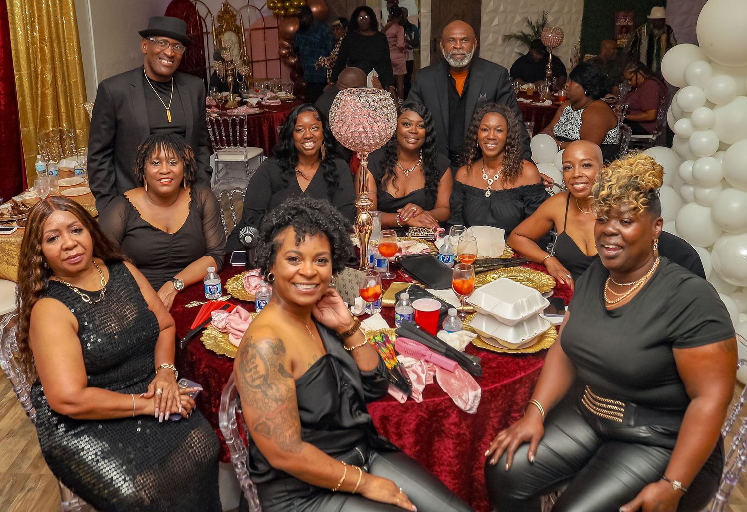 Group of friends in black attire gathered around a decorated table at a festive celebration.