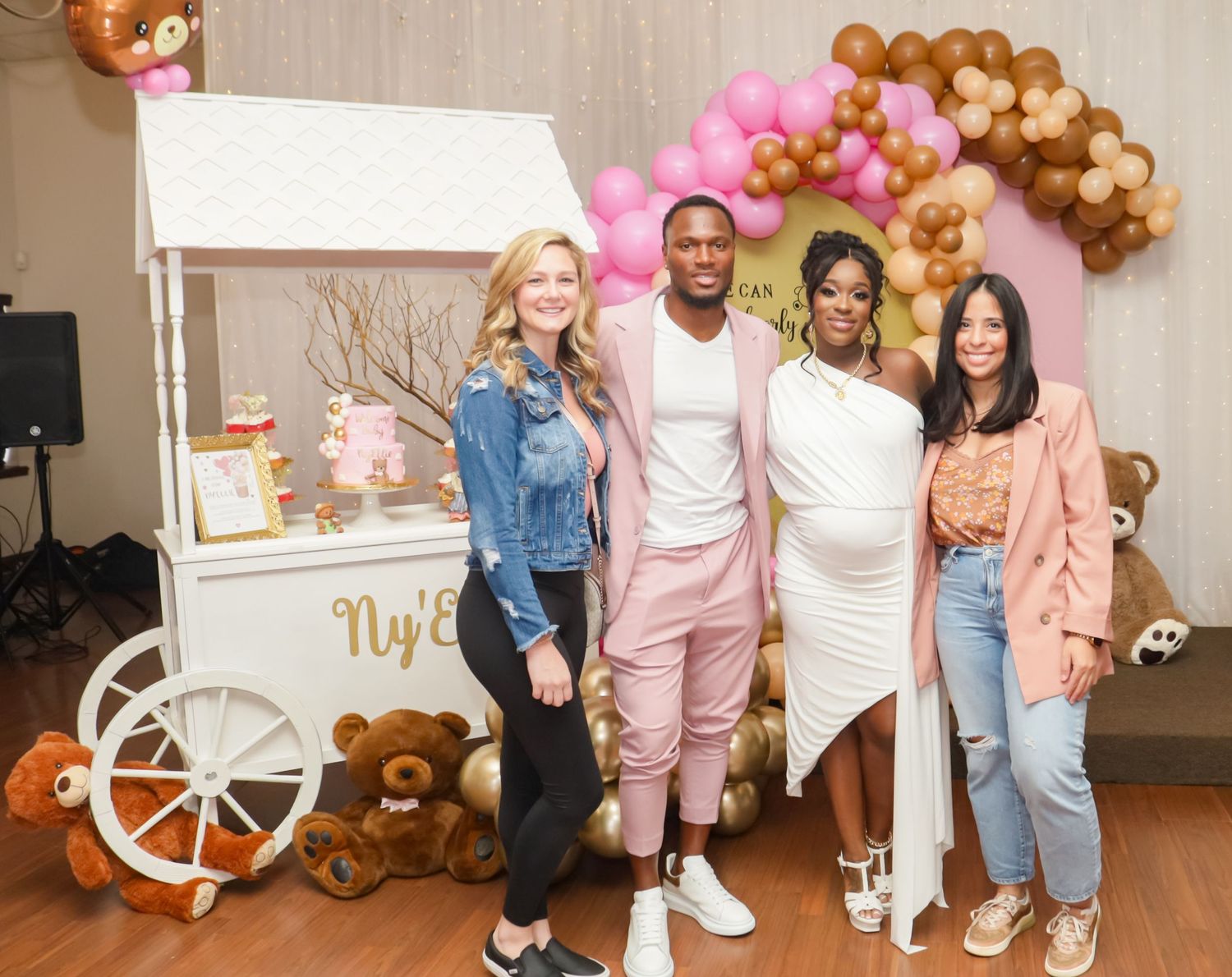 Four guests pose together near dessert cart at pink and gold teddy bear baby shower.