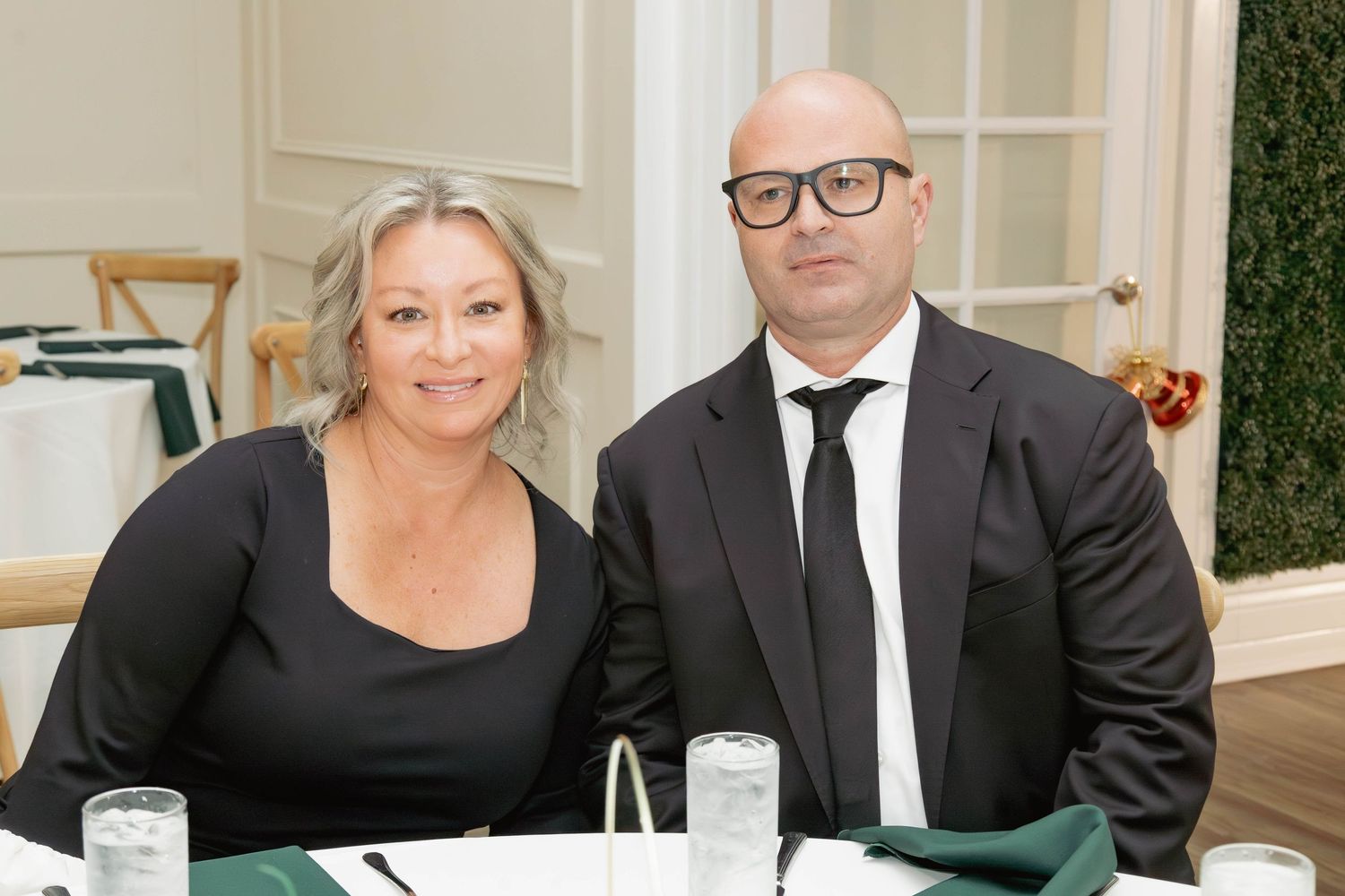 Couple dressed in black formal attire poses together at an elegant banquet dinner event.